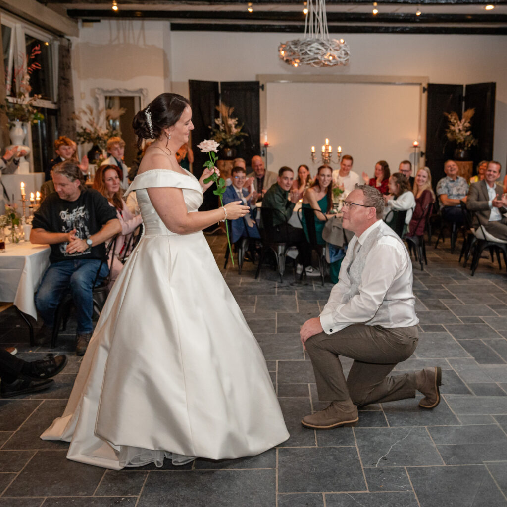 Voor de openngsdans knielt de bruidegom weer voor de bruid. Hij heeft haar net een roos gegeven. Zulke trouwfoto's stralen liefde uit.